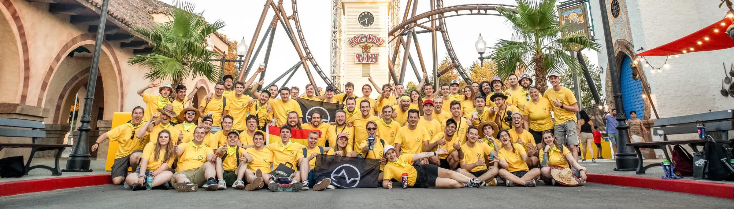 The Seeking The Thrill community in matching yellow shirts in front of a roller coaster